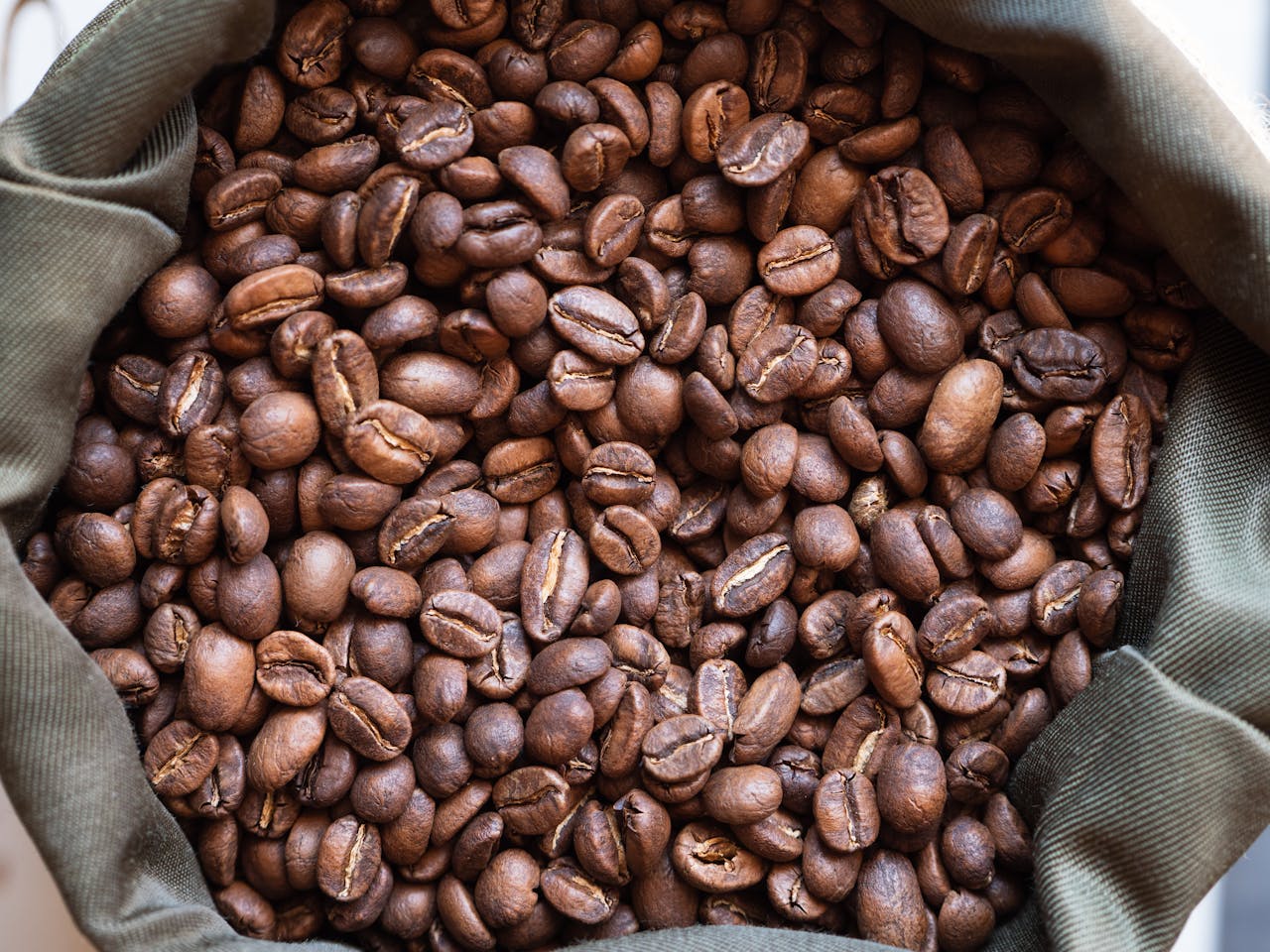 Close-up overhead view of a pile of roasted coffee beans in a bag.