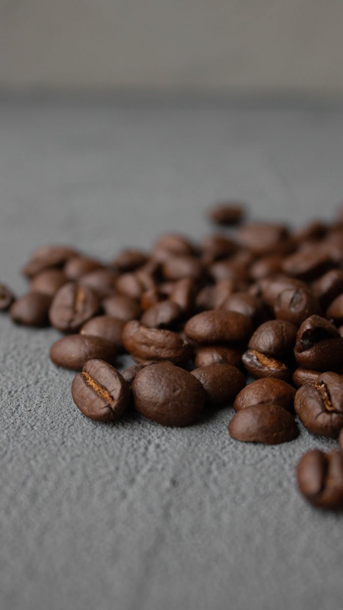 Ground level of pile of aromatic coffee beans scattered on rough gray surface